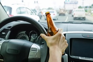 man driving with alcohol bottle in hand